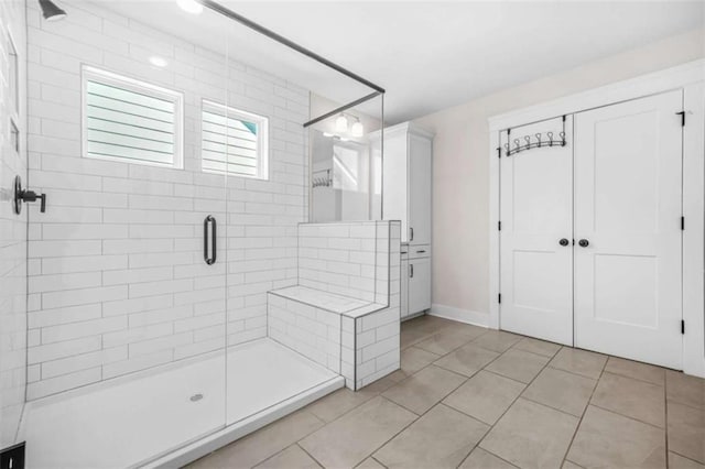 full bath with tile patterned floors, baseboards, and a shower stall
