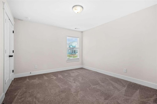 empty room featuring baseboards and carpet