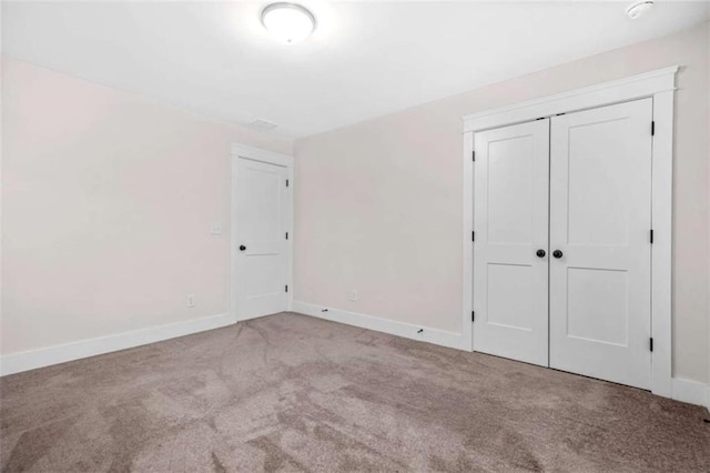 unfurnished bedroom with baseboards, carpet, and a closet