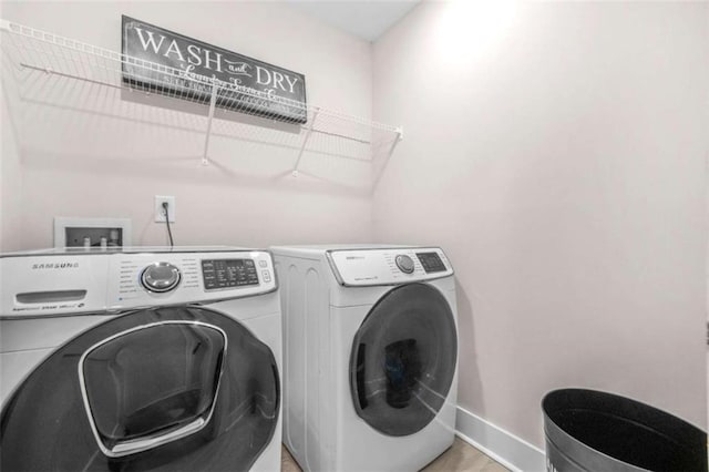 clothes washing area with washer and clothes dryer, baseboards, and laundry area