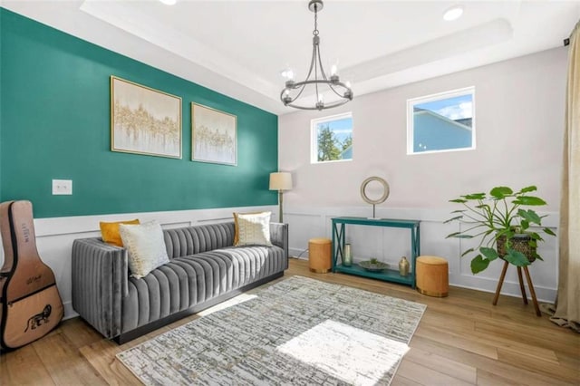 living area featuring wood finished floors, a chandelier, and a tray ceiling