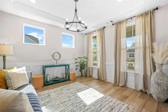 sitting room featuring wainscoting, wood finished floors, a chandelier, and a tray ceiling