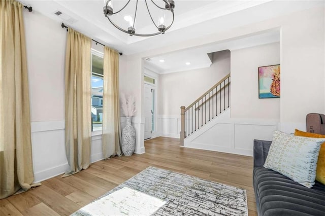 living room with stairs, a wainscoted wall, wood finished floors, and a notable chandelier