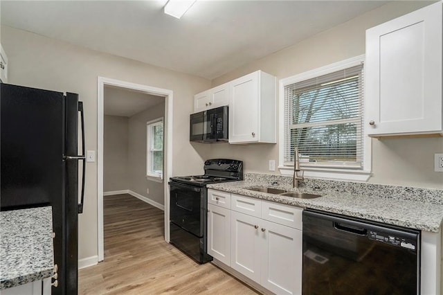 kitchen featuring sink, light stone counters, black appliances, white cabinets, and light wood-type flooring