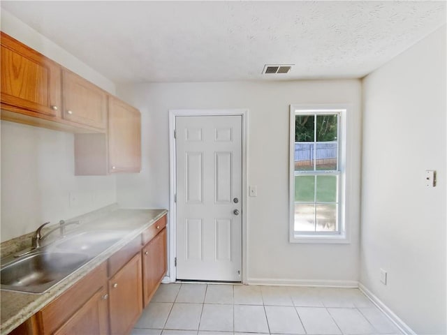 kitchen featuring light tile patterned floors, sink, and a textured ceiling