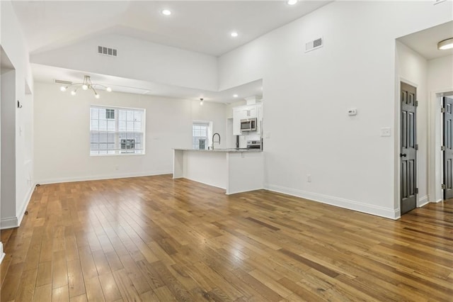 unfurnished living room featuring lofted ceiling, hardwood / wood-style floors, and sink