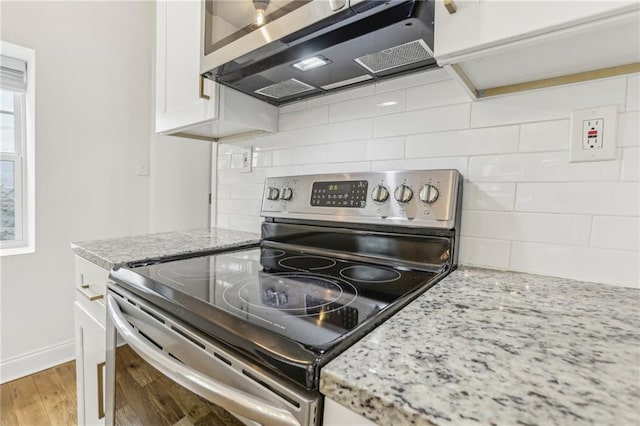 kitchen with white cabinetry, decorative backsplash, stainless steel range with electric stovetop, exhaust hood, and light stone counters