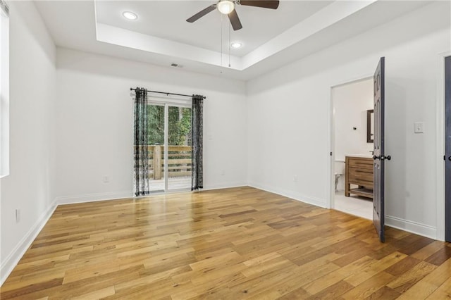 unfurnished room with light hardwood / wood-style flooring, a raised ceiling, and ceiling fan