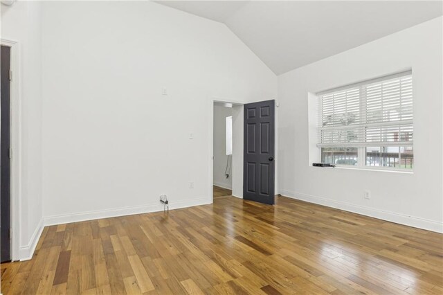 unfurnished room featuring hardwood / wood-style floors and high vaulted ceiling