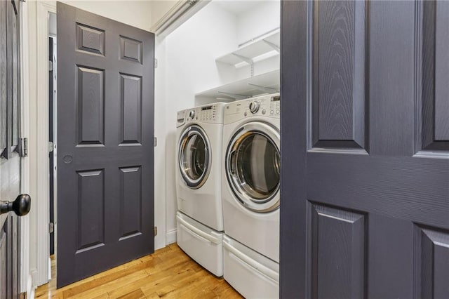 laundry area featuring washer and dryer and light hardwood / wood-style floors