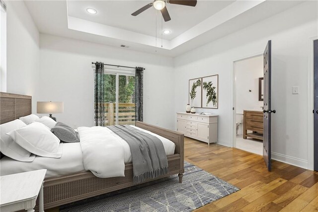 bedroom featuring a raised ceiling, ceiling fan, and light wood-type flooring