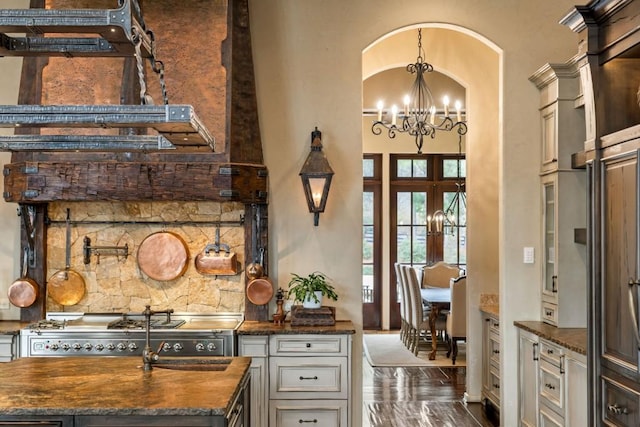 interior space featuring a towering ceiling, a chandelier, french doors, arched walkways, and hanging light fixtures