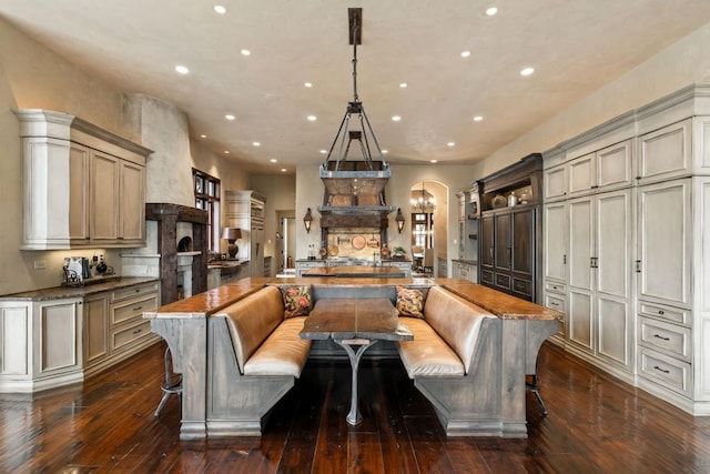 kitchen with a center island with sink, dark wood-style floors, breakfast area, an inviting chandelier, and recessed lighting