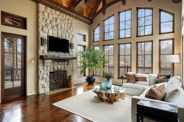 living area with beam ceiling, a fireplace, high vaulted ceiling, hardwood / wood-style floors, and wood ceiling