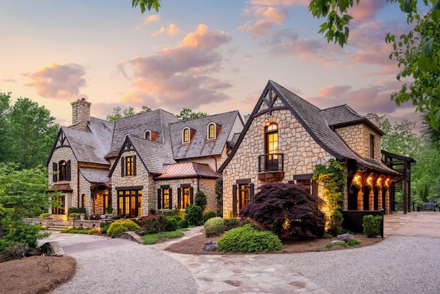 french provincial home with a standing seam roof, a high end roof, a chimney, and stone siding