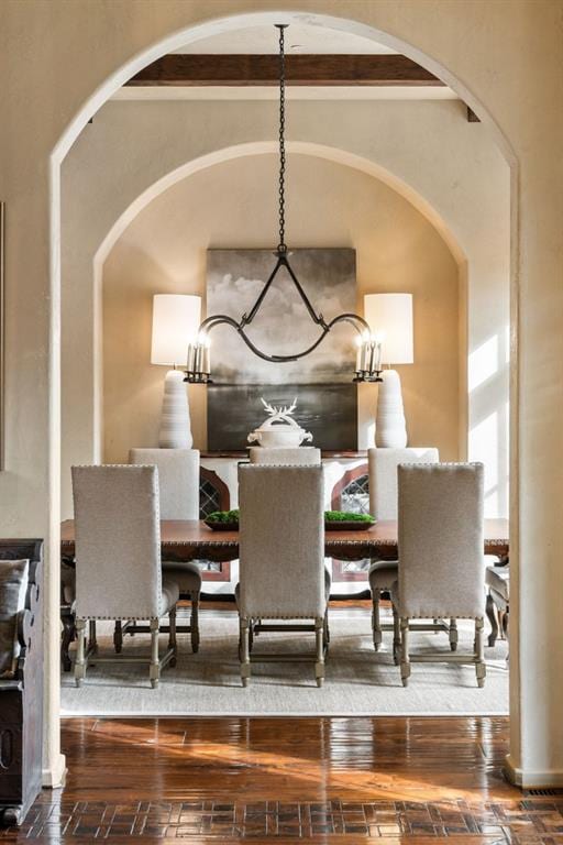 dining area with arched walkways and hardwood / wood-style floors
