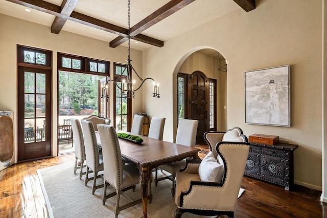 dining area with beam ceiling, hardwood / wood-style floors, arched walkways, coffered ceiling, and a notable chandelier