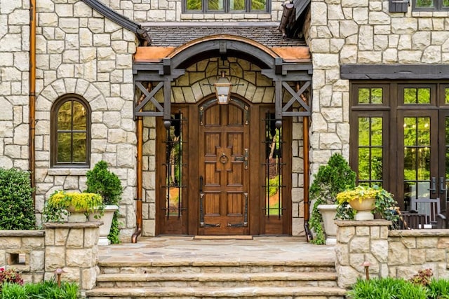 view of exterior entry featuring a high end roof, french doors, and stone siding