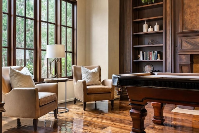 living area with built in features and hardwood / wood-style floors