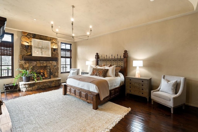 bedroom featuring baseboards, a notable chandelier, hardwood / wood-style flooring, and a fireplace