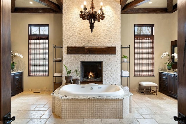 full bath featuring vanity, stone tile floors, and beamed ceiling