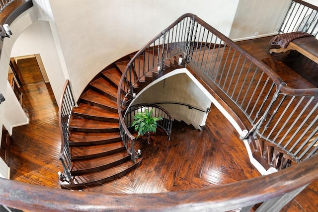 stairway with baseboards, arched walkways, and hardwood / wood-style floors