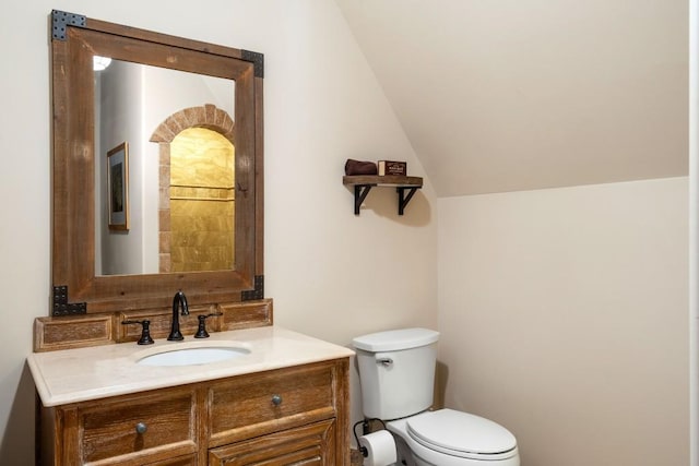 half bathroom featuring vanity, vaulted ceiling, and toilet