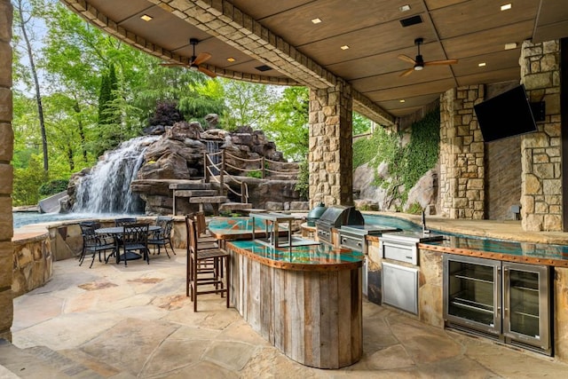 view of patio / terrace featuring outdoor wet bar, wine cooler, exterior kitchen, area for grilling, and a sink