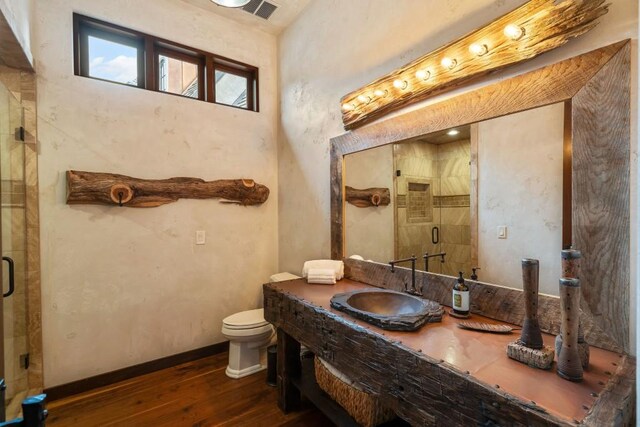 bathroom with a shower stall, toilet, hardwood / wood-style floors, and visible vents