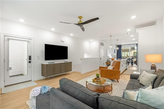 living room featuring visible vents, baseboards, ceiling fan, light wood-type flooring, and recessed lighting