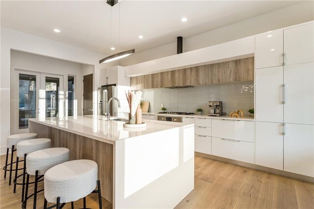 1045 Shepherds Ln NE, Atlanta, GA 30324 - kitchen with stainless steel gas cooktop, light wood-style flooring, modern cabinets, and a breakfast bar area