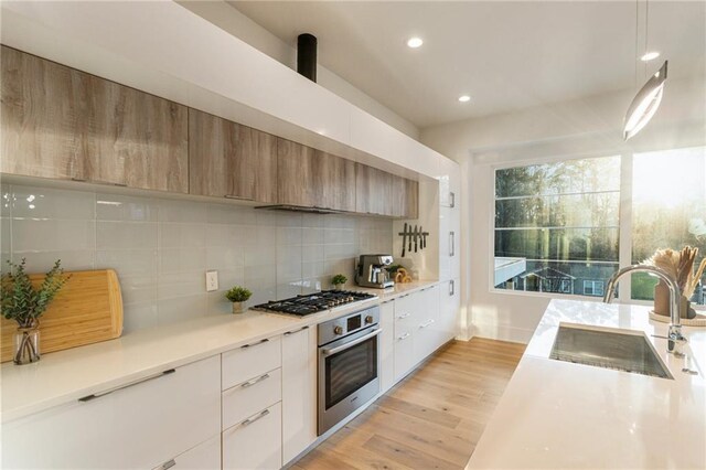 1045 Shepherds Ln NE, Atlanta, GA 30324 - kitchen with decorative backsplash, light wood-style floors, stainless steel appliances, modern cabinets, and a sink