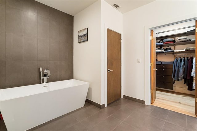 1045 Shepherds Ln NE, Atlanta, GA 30324 - bathroom featuring tile patterned flooring, visible vents, a walk in closet, a freestanding bath, and tile walls