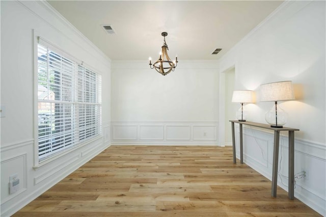 unfurnished dining area with a chandelier, light wood-type flooring, visible vents, and crown molding