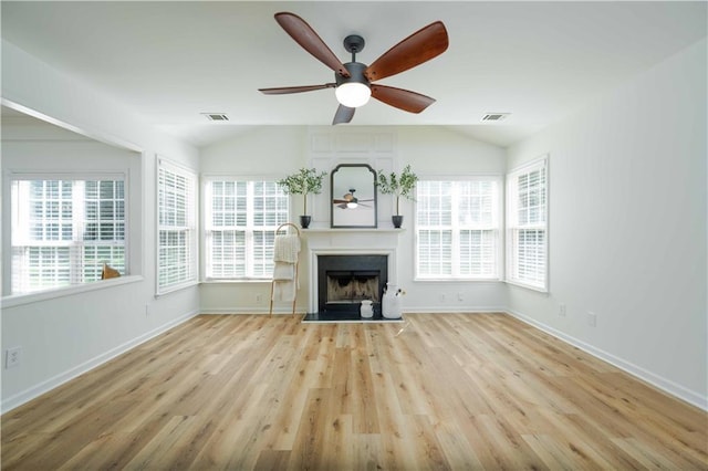 unfurnished living room with plenty of natural light, lofted ceiling, visible vents, and a fireplace