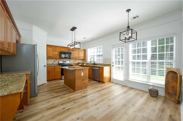 kitchen featuring visible vents, brown cabinetry, ornamental molding, appliances with stainless steel finishes, and a center island