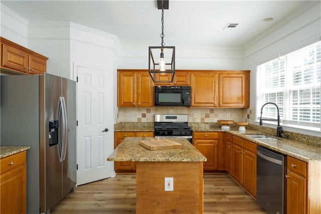 kitchen featuring visible vents, appliances with stainless steel finishes, crown molding, light wood-style floors, and a sink