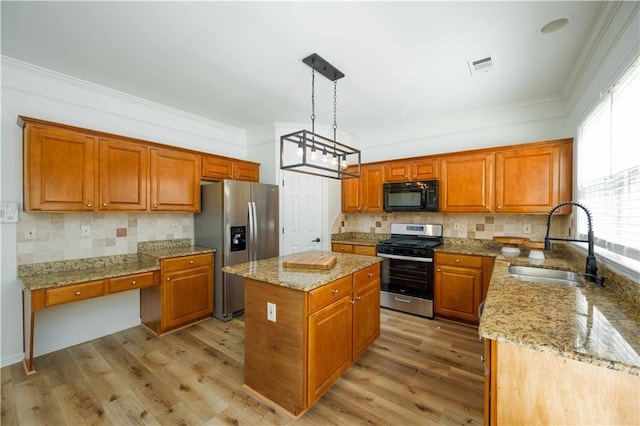 kitchen with visible vents, appliances with stainless steel finishes, brown cabinetry, a sink, and a kitchen island