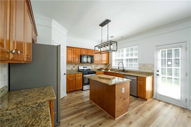 kitchen featuring light stone counters, brown cabinets, ornamental molding, stainless steel appliances, and a sink