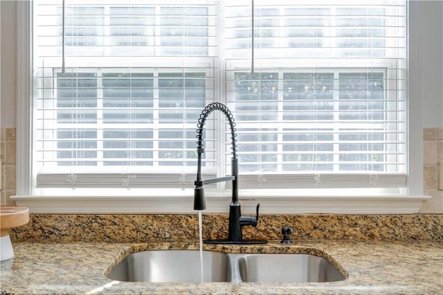 room details featuring light stone counters and a sink