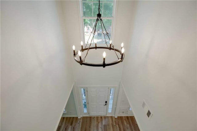 entryway with wood finished floors, visible vents, and a notable chandelier