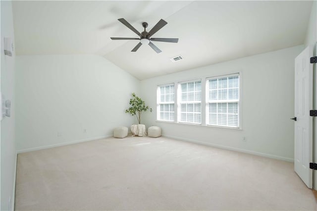 unfurnished room featuring vaulted ceiling, light carpet, visible vents, and baseboards