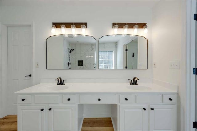 bathroom with double vanity, walk in shower, and a sink