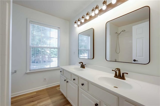 bathroom with double vanity, a sink, baseboards, and wood finished floors