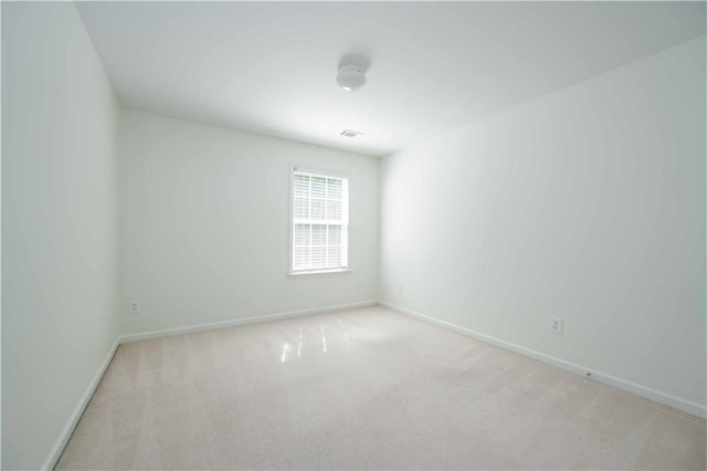 spare room featuring carpet floors, visible vents, and baseboards