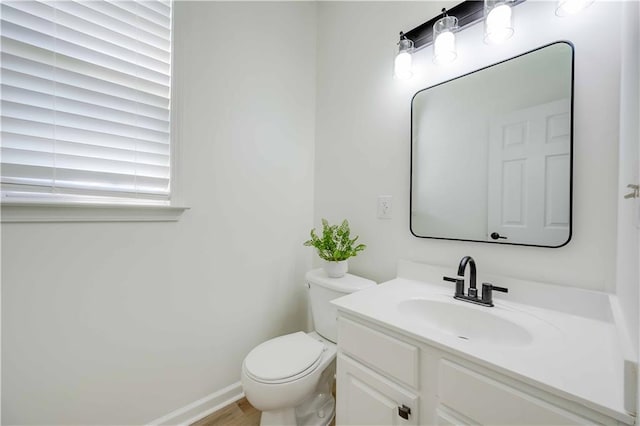 half bathroom featuring baseboards, vanity, and toilet