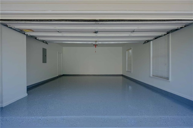 garage featuring a garage door opener, electric panel, and baseboards