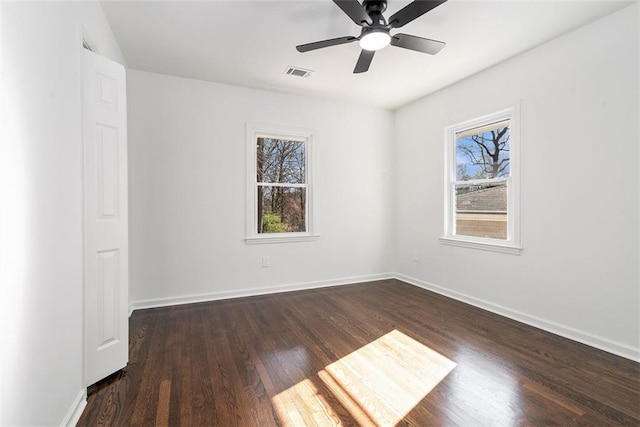 spare room featuring dark hardwood / wood-style flooring, ceiling fan, and plenty of natural light