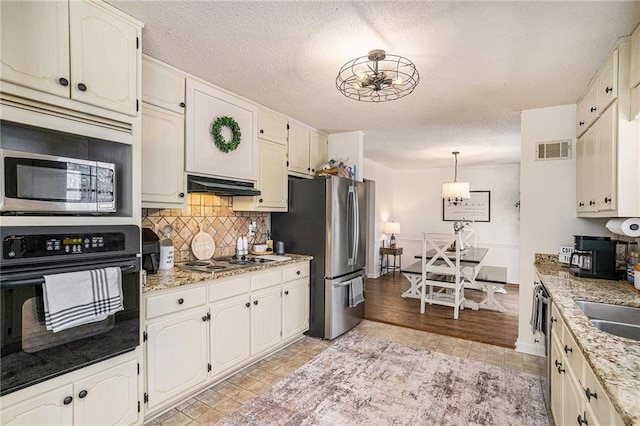 kitchen with visible vents, under cabinet range hood, backsplash, a textured ceiling, and appliances with stainless steel finishes