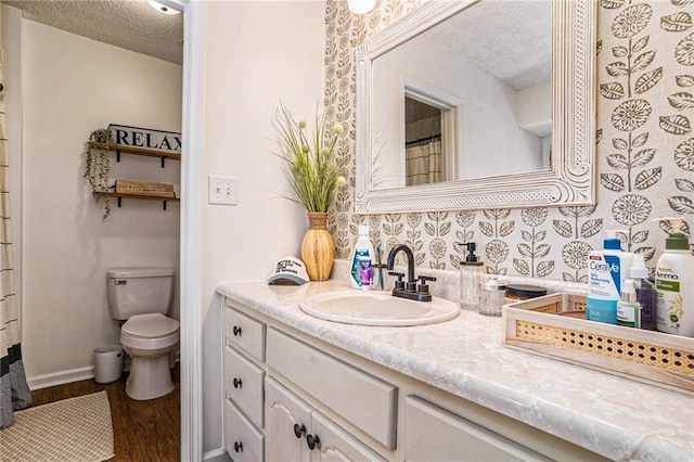full bathroom featuring baseboards, toilet, vanity, wood finished floors, and a textured ceiling